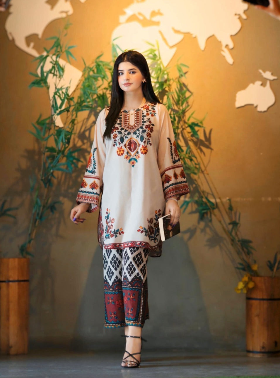 Woman in traditional embroidered outfit standing in front of a world map backdrop