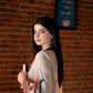 Woman holding a cup against a brick wall