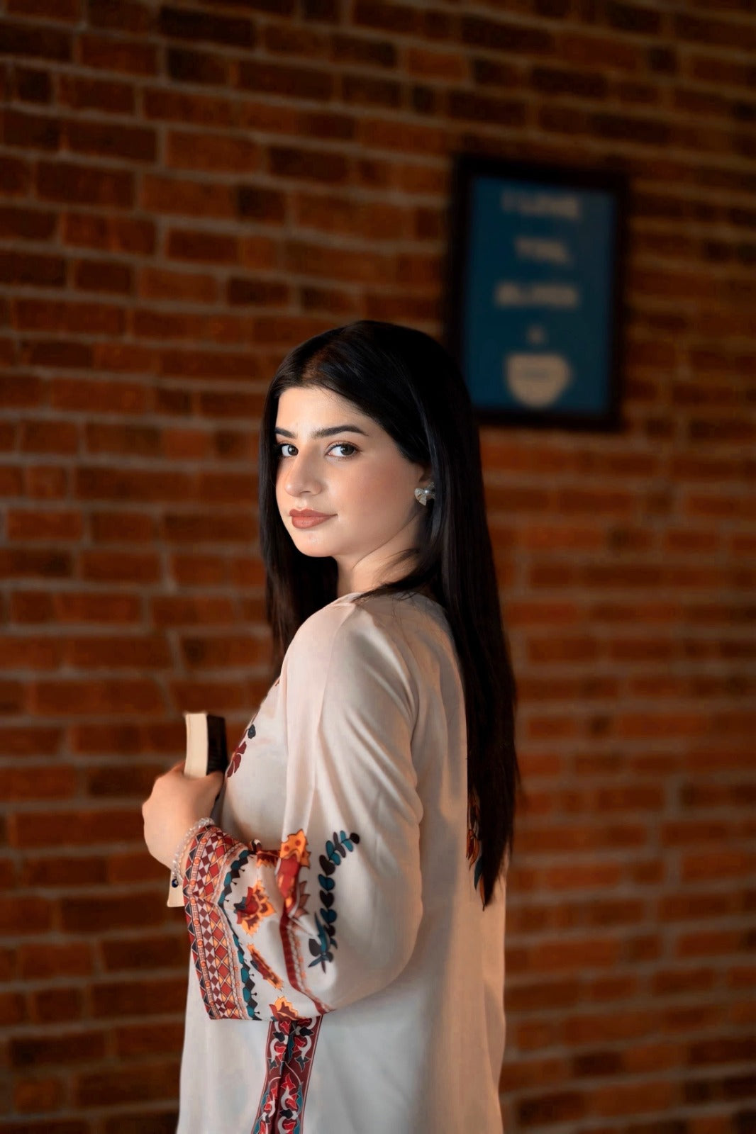 Woman holding a cup against a brick wall