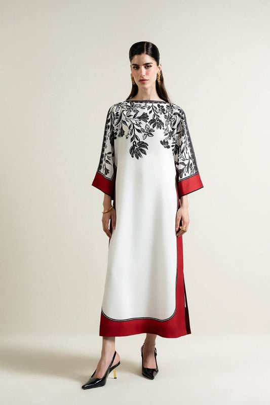 Woman wearing a white dress with black floral patterns and red accents on a plain background