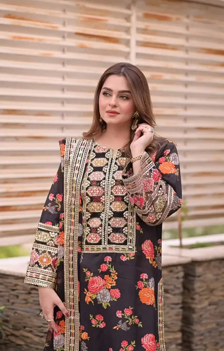 Woman wearing a black embroidered outfit with floral patterns against a wooden background