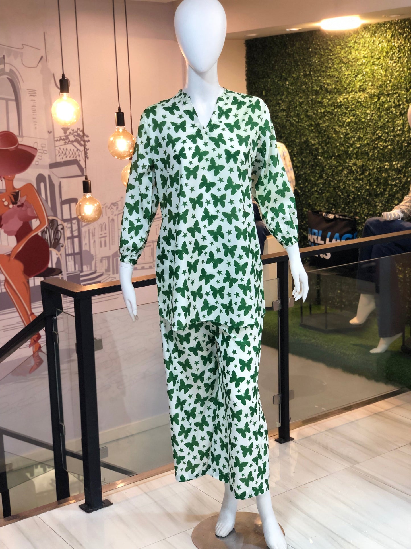 Mannequin wearing a green and white patterned dress in a store setting.