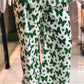 Green butterfly patterned pants on a mannequin against a blurred indoor background