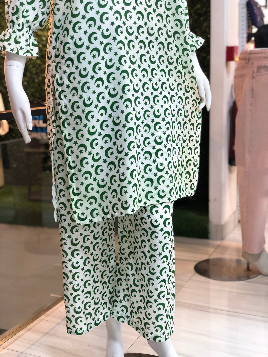 Green and white patterned outfit on a mannequin in a store setting