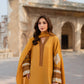 Woman in a mustard yellow dress with intricate patterns standing in front of historical architecture.