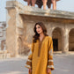 Woman in a yellow dress standing in front of an architectural structure.