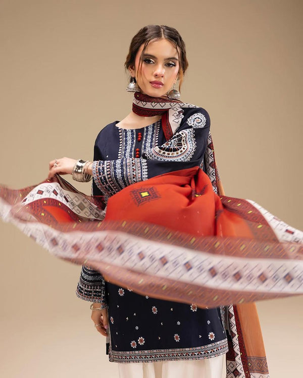 Woman holding a traditional outfit with a red and navy patterned fabric against a beige background