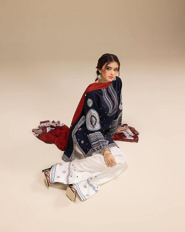 Woman wearing a traditional outfit with a red dupatta and white pants on a beige background