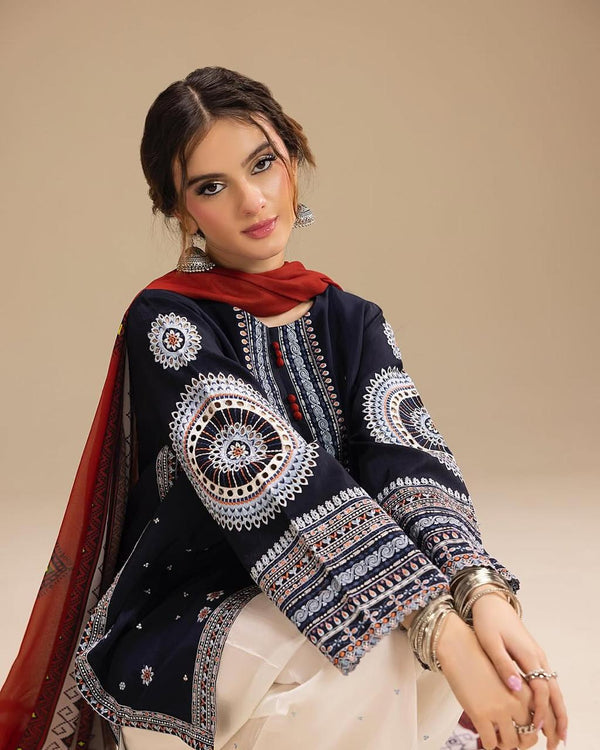 Woman wearing a traditional embroidered outfit with a red scarf on a beige background