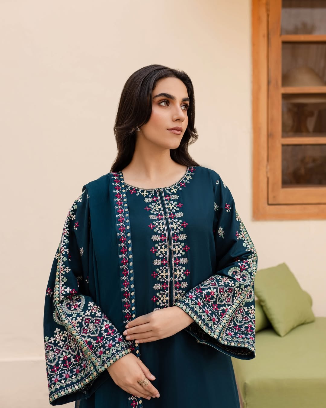 Woman wearing a dark blue embroidered dress in an indoor setting.