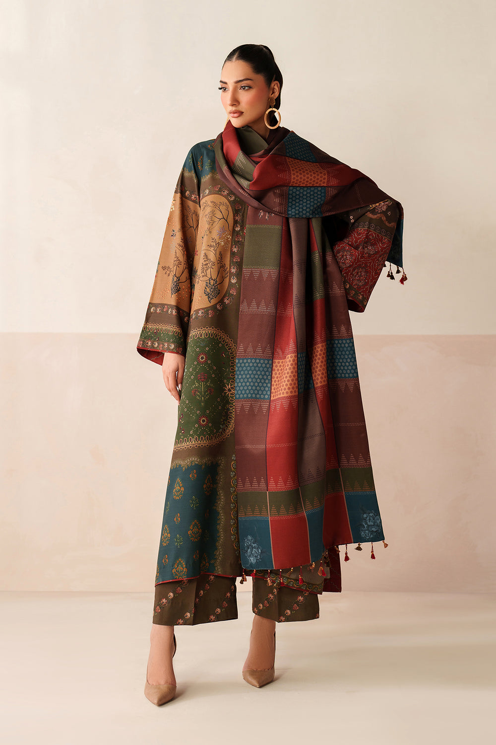 Woman wearing a long, patterned coat with a matching scarf against a beige background