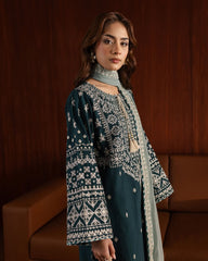 Woman wearing a traditional outfit with intricate patterns in a warm-toned room.